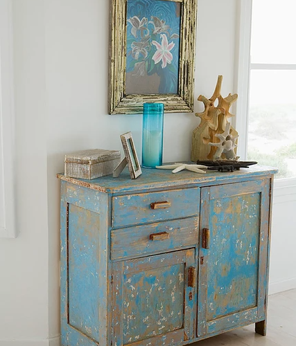 Blue desk with painting hanging on the wall above it.